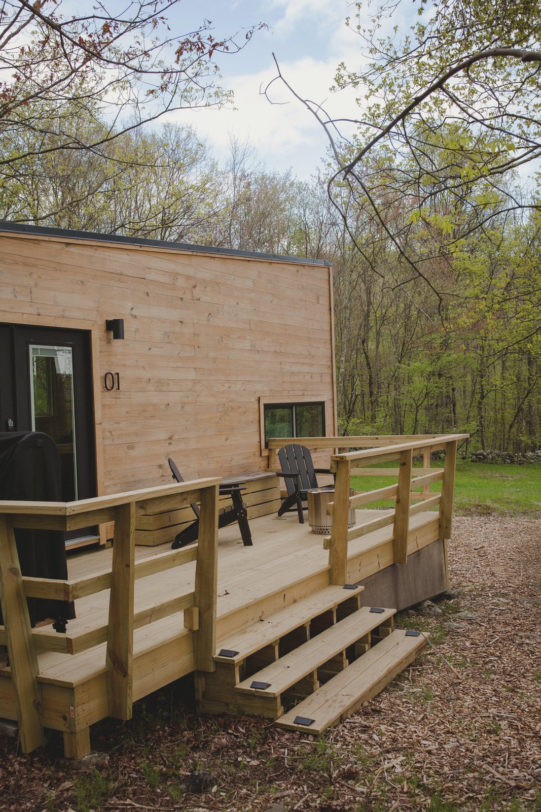 The cabin from the front, its number painted beside the door, with a timber deck and steps down to the ground