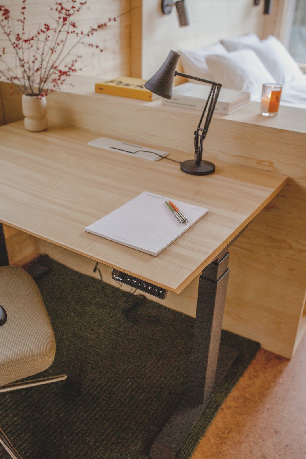 A desk and task lamp against the pine wall, with a window beside it