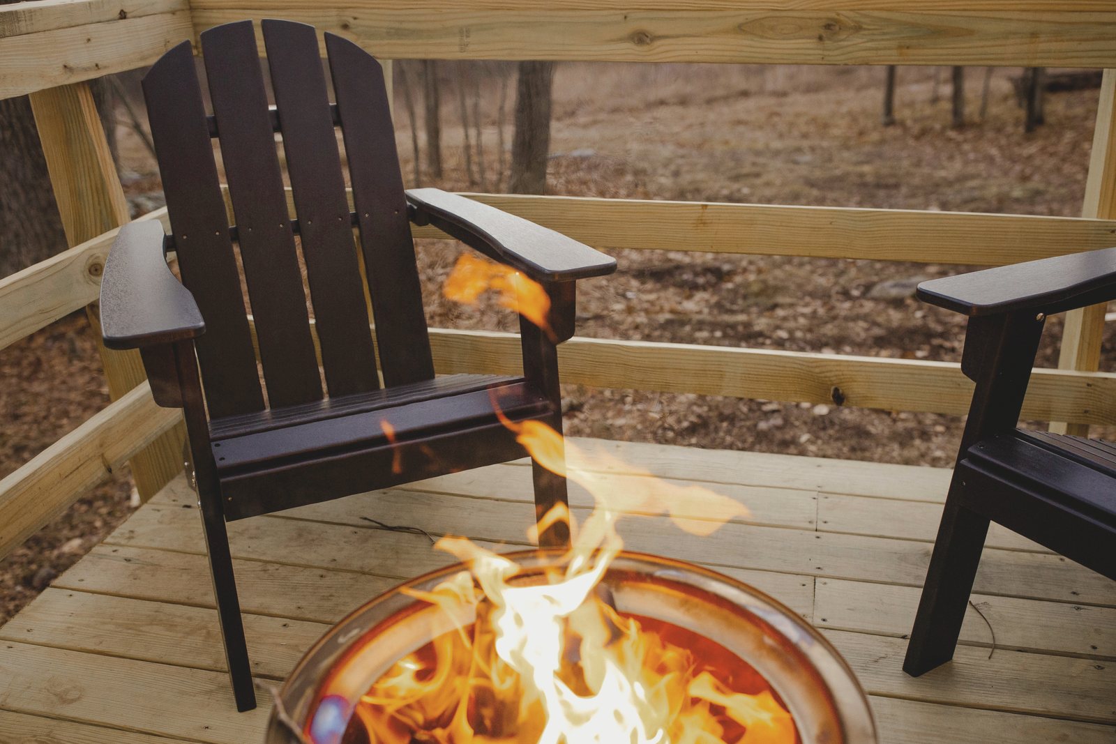 Two chairs pulled up to a lit fire pit on the deck